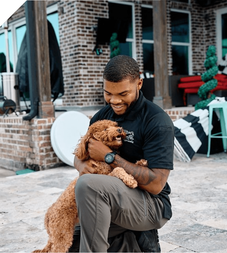 Man happily holding a small brown dog outdoors.