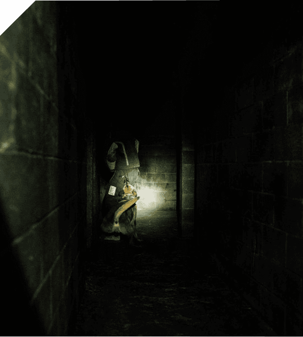 A person exploring a dark, eerie corridor with a flashlight.