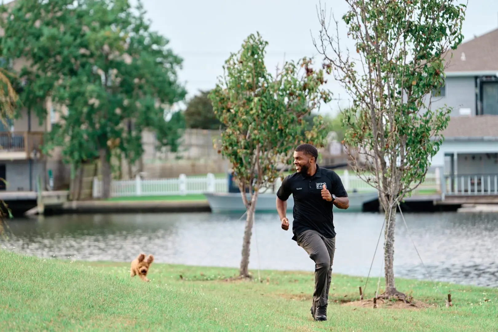 Man running in park with small dog nearby.