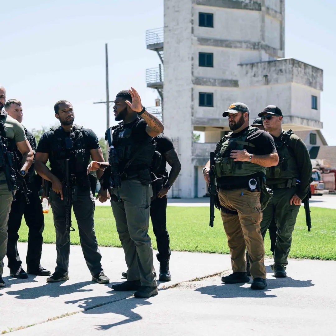 Group of armed security personnel standing outdoors near a building.