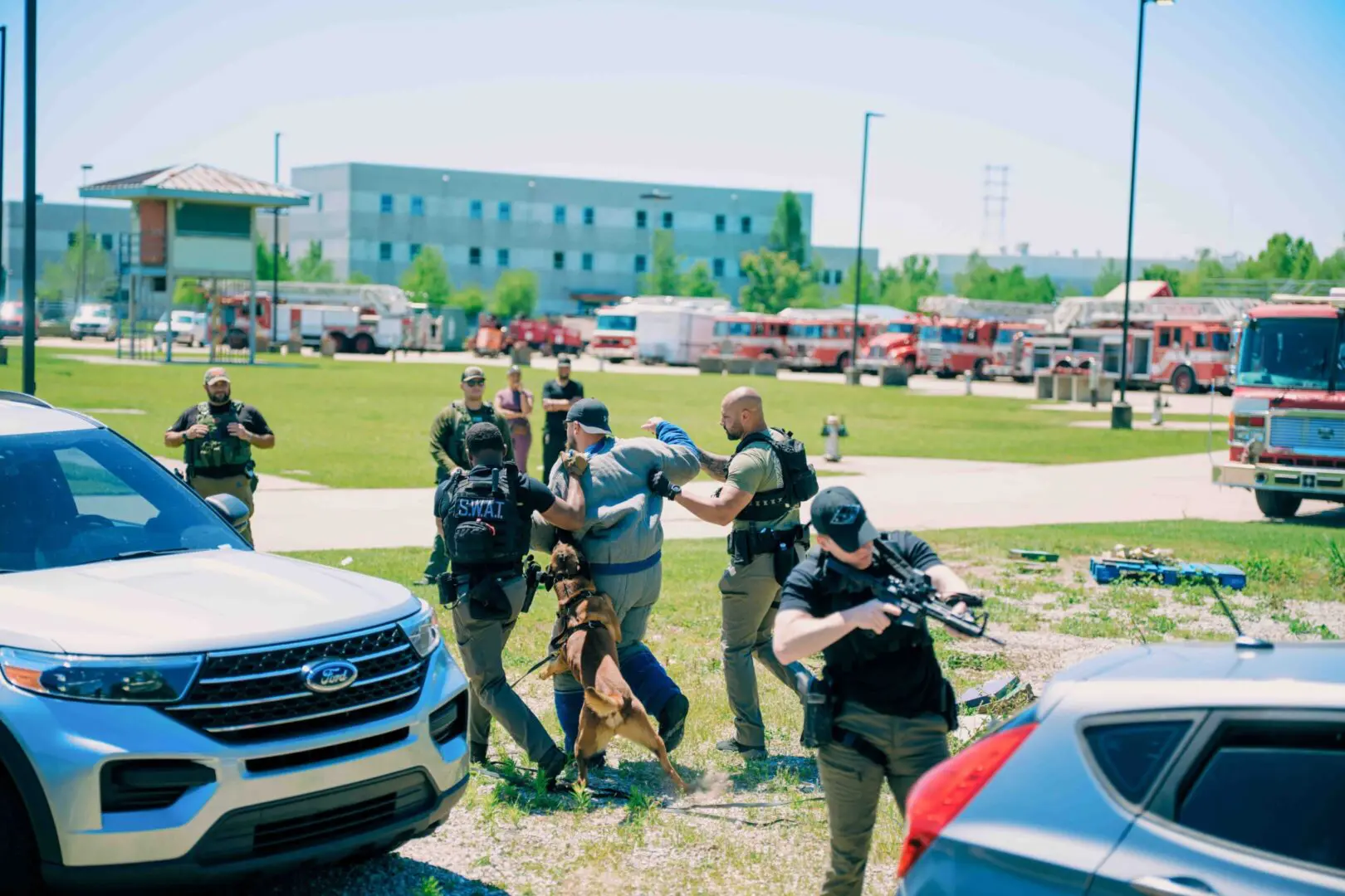 Law enforcement officers detaining a suspect outdoors near vehicles.