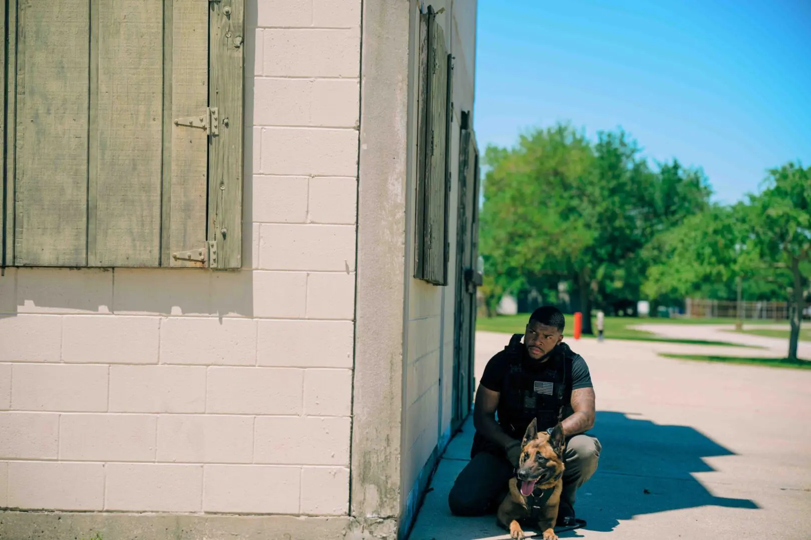 Person sitting against a white building wall with a dog.