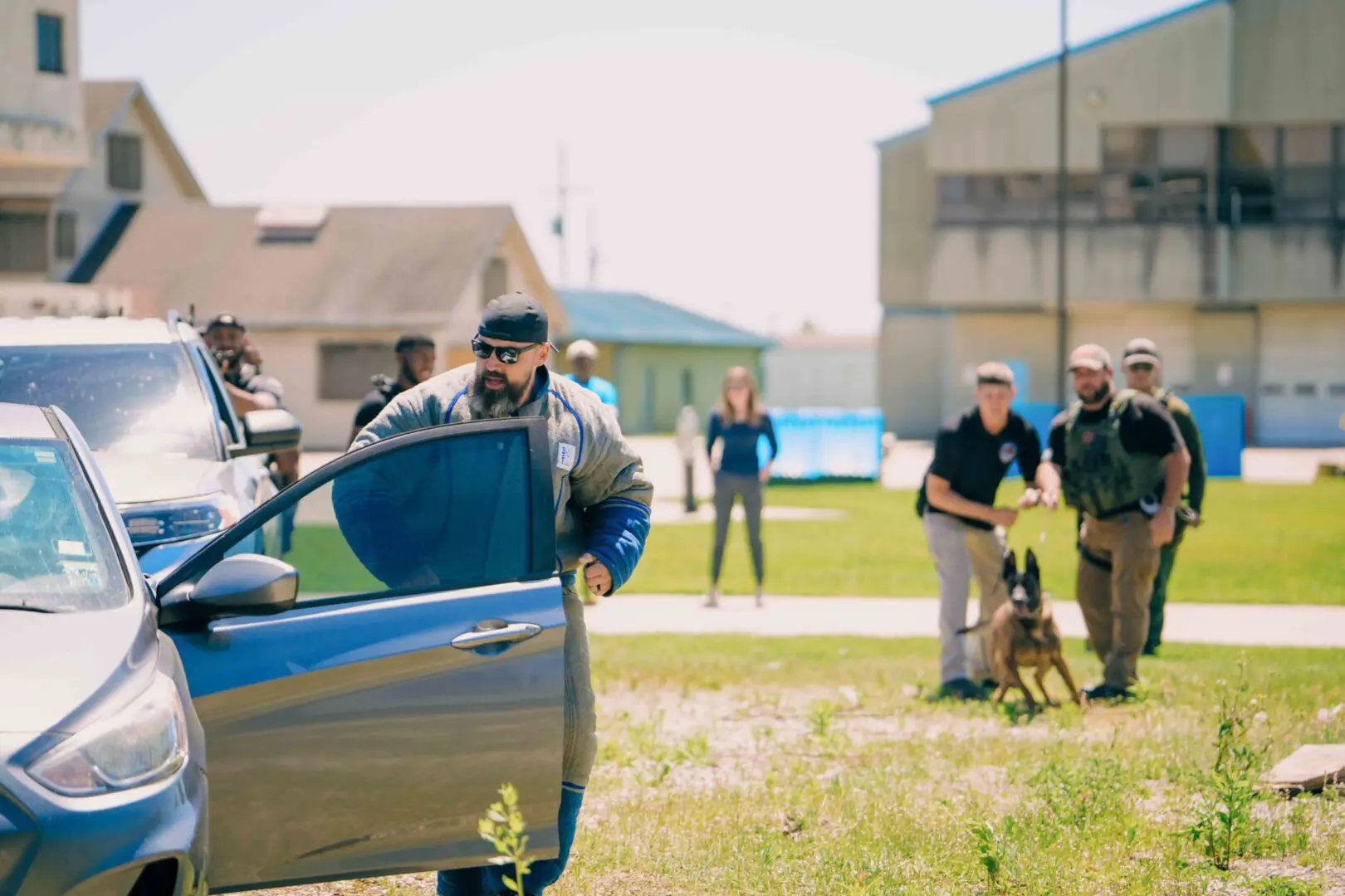 Police officer inspecting a car while an elderly man with a walker walks nearby.