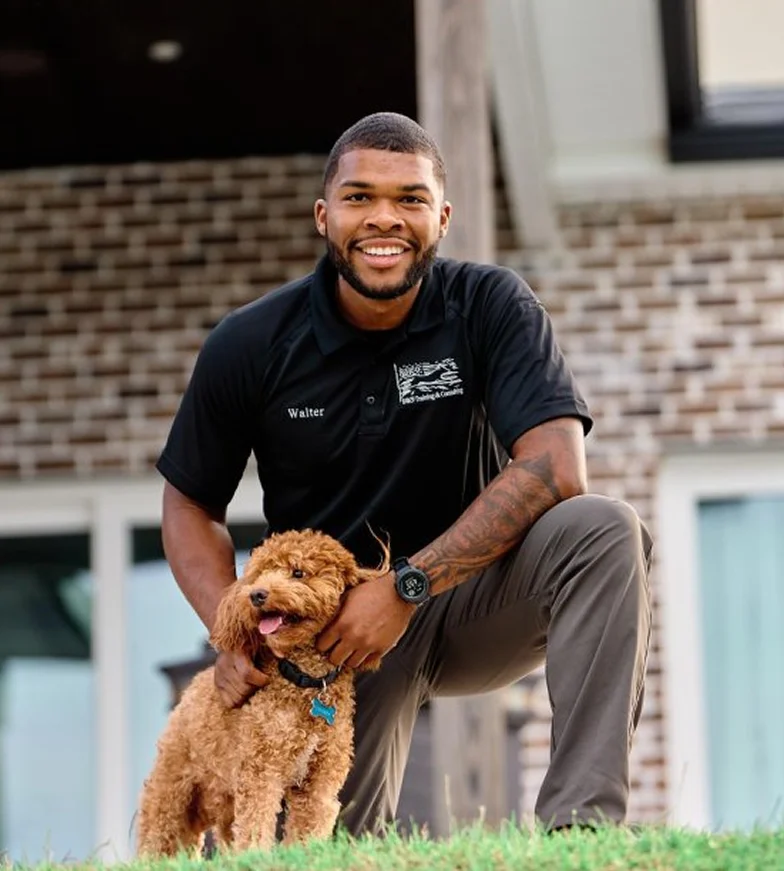 Smiling man with a dog outside a modern house.